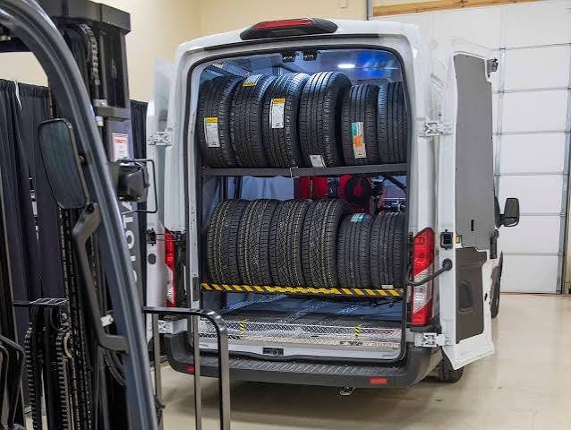 Back doors open on a mobile tire service van, showing a fully loaded rack of new tires